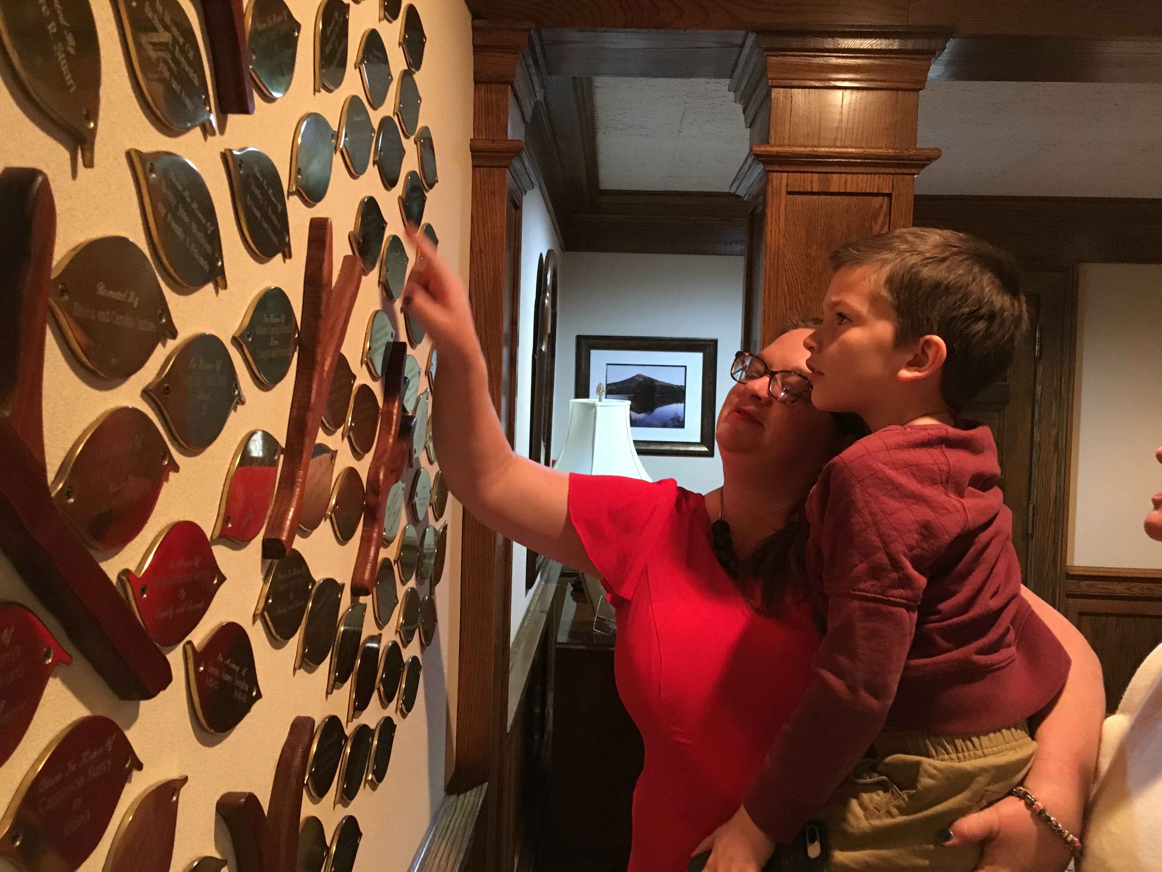 Mother and son look at mounted tree mural with engraved writing in the House